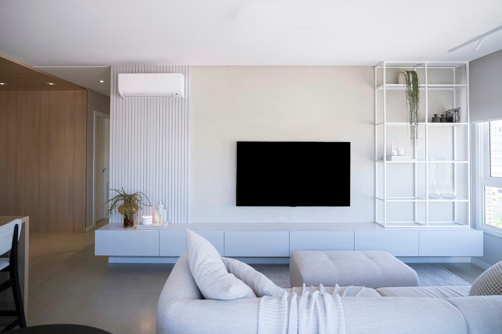 Large TV mounted in a bright living room with white furniture